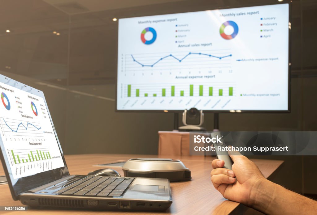 Businessman hand hold remote control slide with presentation on display laptop and television Slide Show Stock Photo