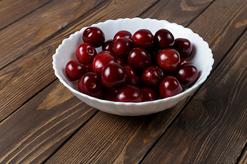sweet cherry in a white plate on a wooden background. copy space