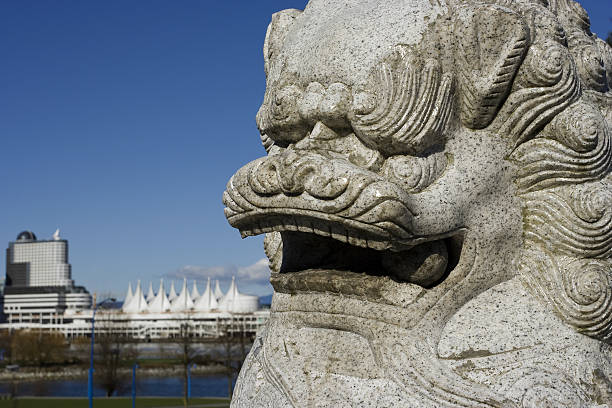 Chinese lion statue in front of view of Canada Place in Vancouver