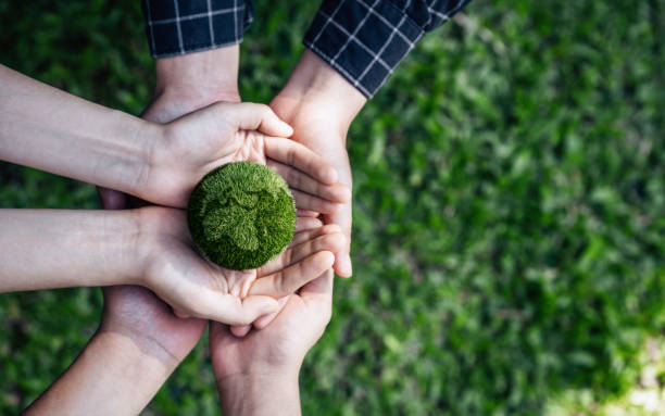 vista dall'alto le mani delle persone che abbracciano un globo fatto a mano per proteggere il pianeta insieme nel concetto di giornata mondiale della terra. energia verde, esg, energie rinnovabili e risorse sostenibili. cura dell'ambiente. - environment nature child people foto e immagini stock