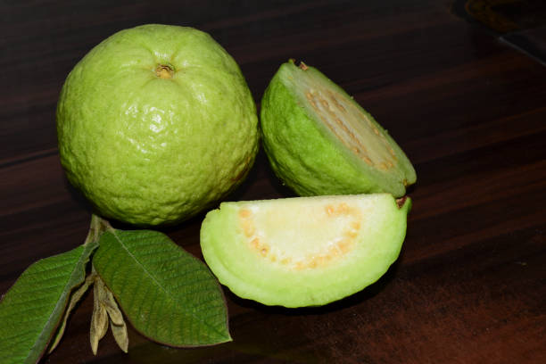 istock Fresh guava fruit with green leaf on the wooden table 1452442015