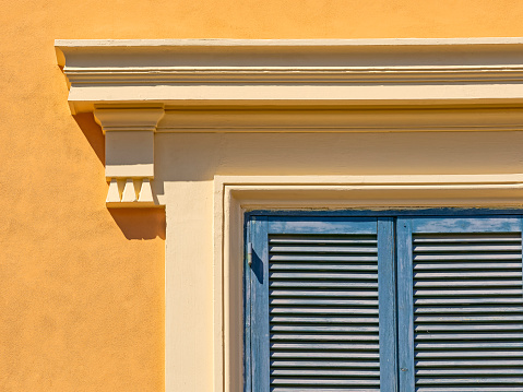 two building next to each other, painted different colors, each with closed wooden window shutters of different colors, in the downtown area of Vedelago, Italy, Treviso, Veneto
