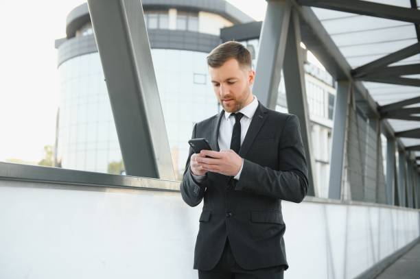 istock Confident young businessman using cell phone in the city. 1452445730