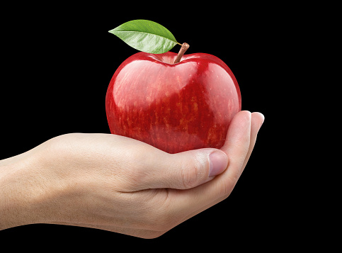 Hand holding delicious red apple, isolated on black background