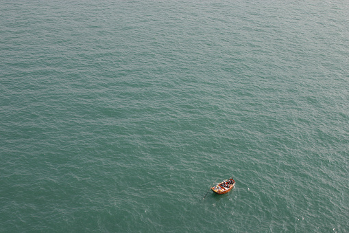 An aerial view of a small boat on a large expanse of calm open ocean.