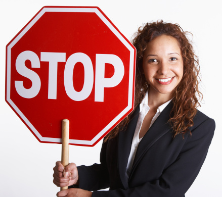 smiling young business woman holding up a STOP sign