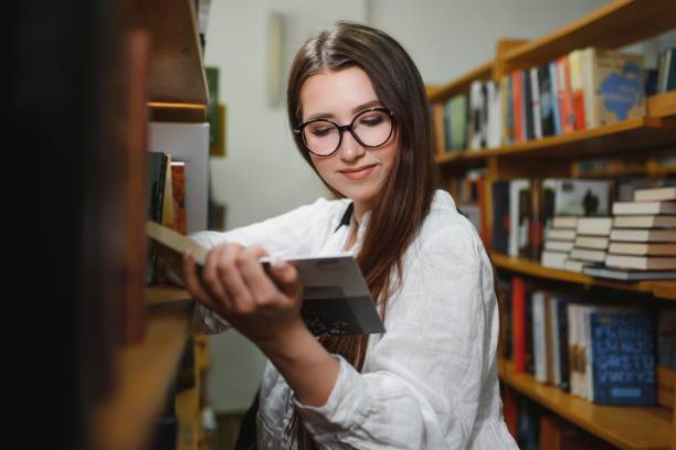 istock in the library - pretty female student with books working in a high school library. 1452454026