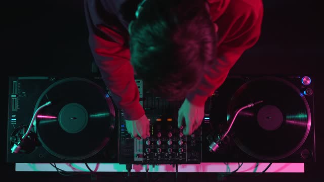 Club DJ playing music on a hip hop party. Overhead video clip of a disc jockey mixing vinyls on stage