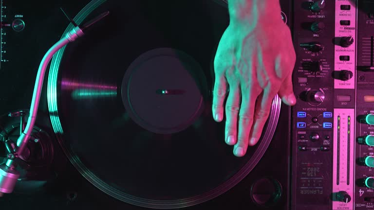 Dj scratching vinyl record, filmed directly from above on concert stage. Professional disc jockey scratches disc on turntable in overhead video clip