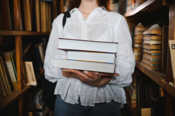 istock in the library - pretty female student with books working in a high school library. 1452455609