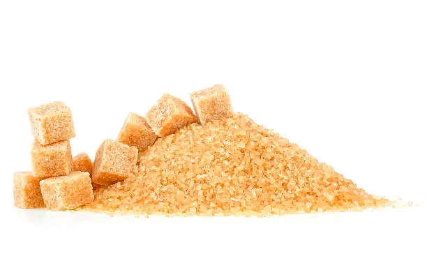 Crystals of cane sugar and brown sugar cubes isolated on a white background. Brown caramel cane sugar.