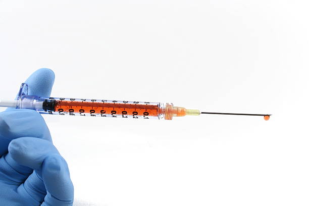 gloved hand with filled syringe and needle stock photo