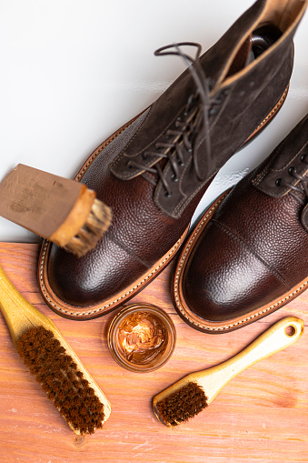 View of Various Shoes Cleaning Accessories for Dark Brown Grain Brogue Derby Boots Made of Calf Leather with Special Tools. Vertical image Orientation