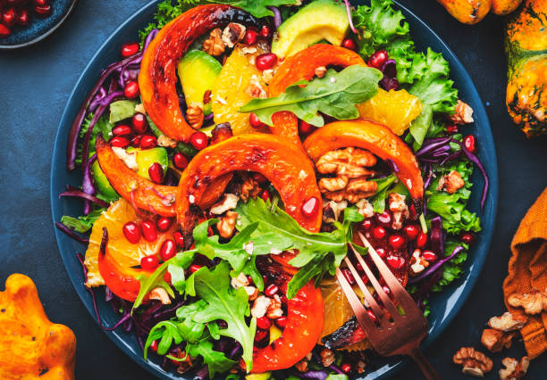 istock Fresh pumpkin salad with lettuce,  red cabbage, avocado, arugula, pomegranate seeds and nuts. Healthy vegan vegetarian eating, slow comfort food. Blue table background. Top view 1452468913
