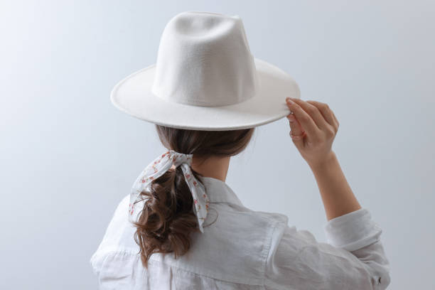 istock Young woman with hat and stylish bandana on light background, back view 1452469151