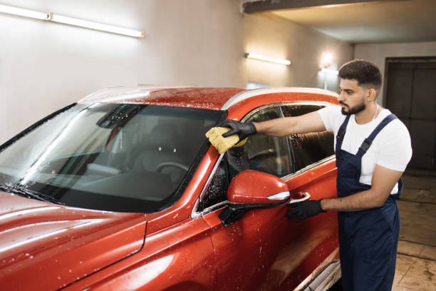 istock Attractive handsome young bearded man washing a soapy car windshield with a yellow sponge. 1452469753