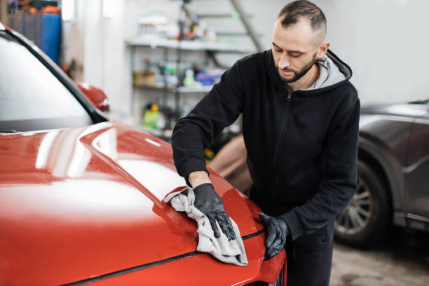 istock Young car wash worker man, wearing protective gloves, wiping modern car with microfiber cloth 1452469890