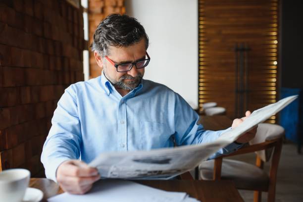 istock active senior man reading newspaper and drinking coffee in restaurant 1452470428