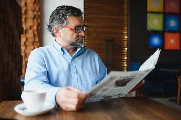 istock active senior man reading newspaper and drinking coffee in restaurant 1452470434