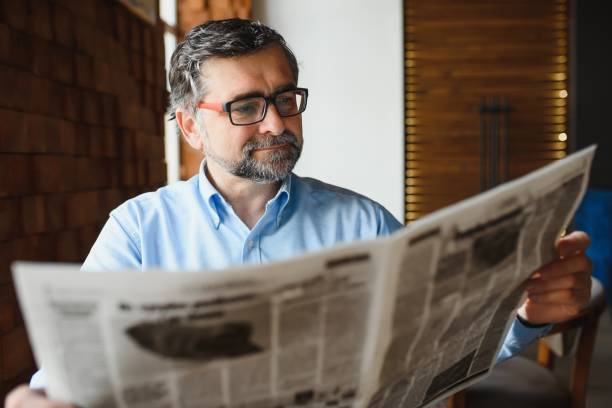 istock active senior man reading newspaper and drinking coffee in restaurant 1452470520