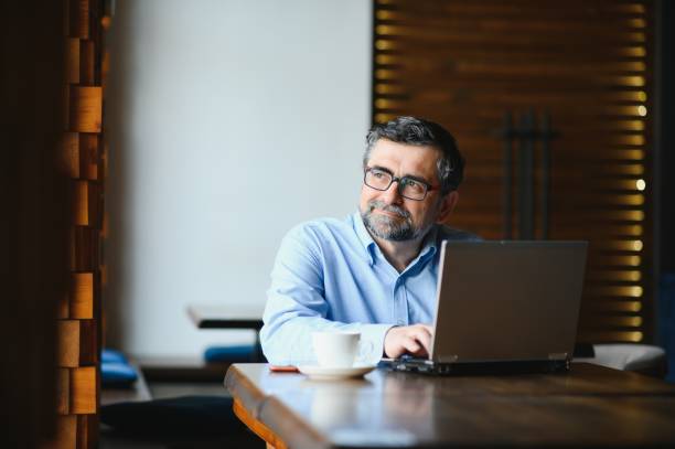 istock Business, technology and people concept , senior businessman with laptop computer drinking coffee at modern cafe. 1452470962