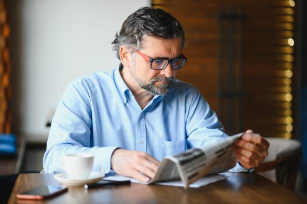 istock active senior man reading newspaper and drinking coffee in restaurant 1452471167