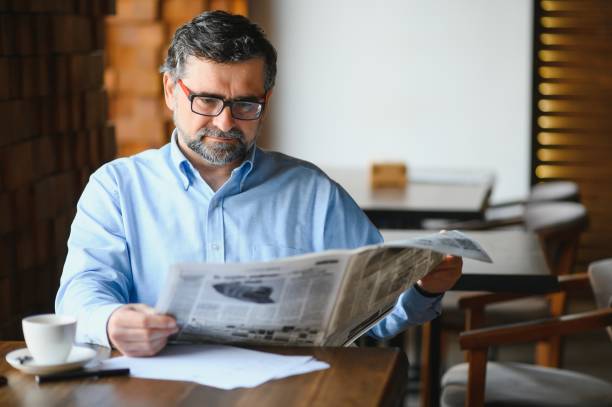 istock coffee break. man drinking coffee and reading newspaper in cafe bar 1452471218