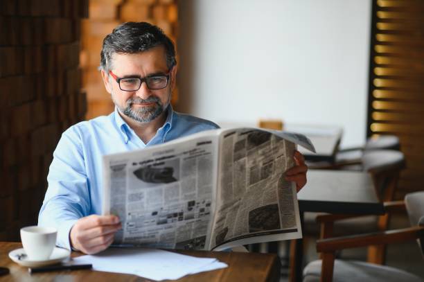 istock active senior man reading newspaper and drinking coffee in restaurant 1452471219