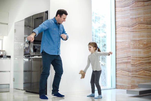 istock Father and daughter dancing in corridor by window at home 1452473199