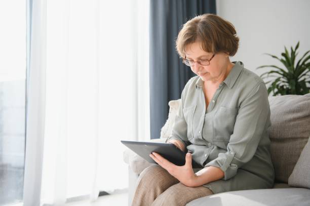 istock Smiling senior woman at home connected on internet 1452473339