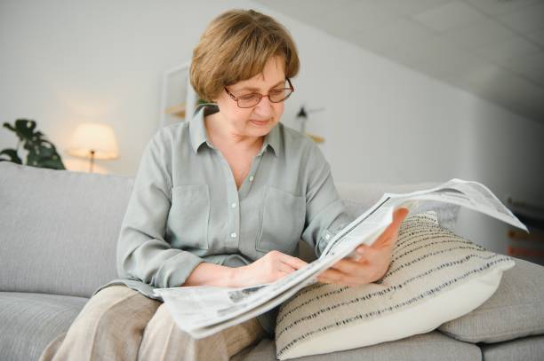 istock Woman in bedroom with newspaper smiling 1452473601
