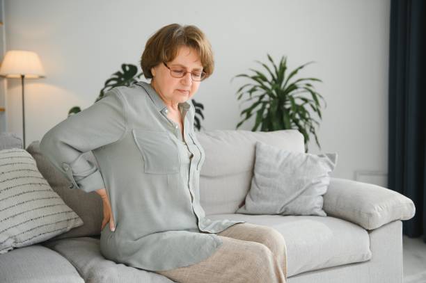 istock Senior woman suffering from back pain on sofa at home 1452473722