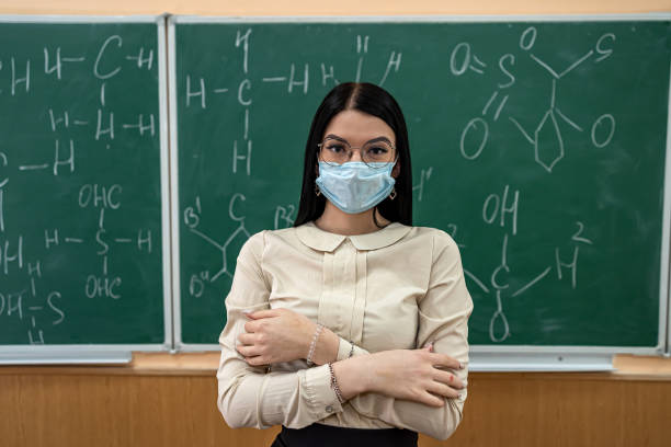 istock young female teacher in protective mask standing near blackboard 1452474744