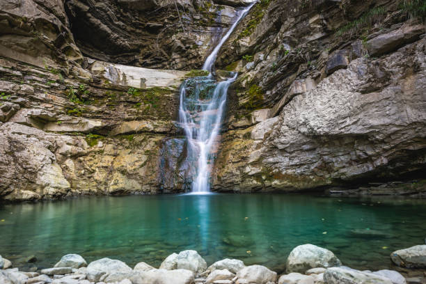 istock wonderful small waterfall that forms a pond of emerald water in a forest 1452475824