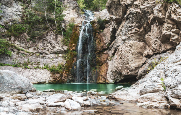 istock wonderful small waterfall that forms a pond of emerald water in a forest 1452475825