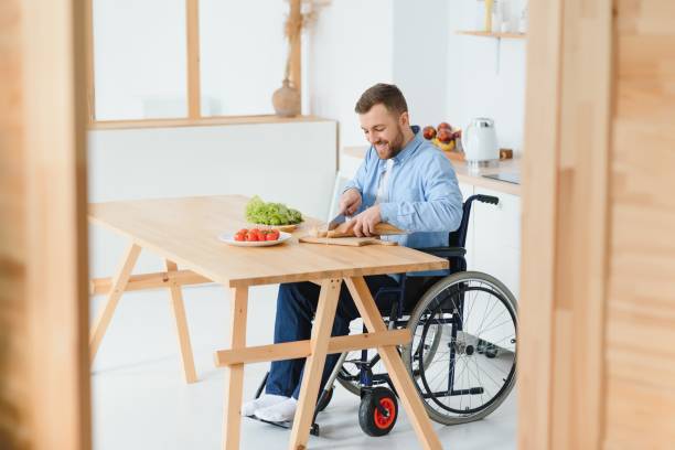 istock Young Disabled Man Sitting On Wheel Chair Preparing Food In Kitchen 1452476649