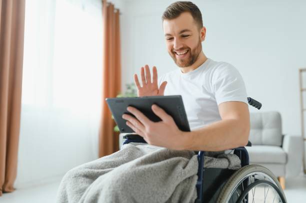 istock Modern young disabled man in wheelchair having video call 1452477362