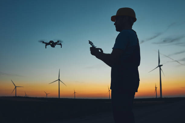 Engineer mechanic using drone for inspection in a windmill farm park.