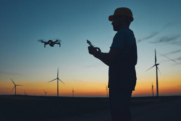 Engineer mechanic using drone for inspection in a windmill farm park. stock photo
