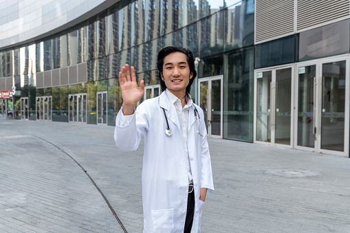 Smiling doctor waving communicating with patient online
