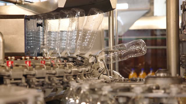 Machine filling plastic bottles with juice at the beverage factory