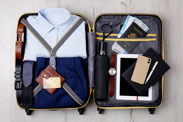 istock Packed suitcase with business trip stuff on wooden surface, top view 1452485672