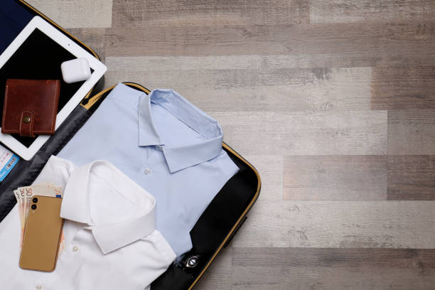 istock Packed suitcase with business trip stuff on wooden surface, top view. Space for text 1452485681