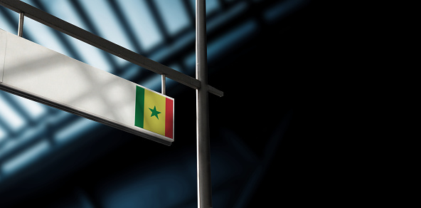 Flag of Senegal on airport departure information board. Close-up. Roof construction in the background. Blue color. Horizontal orientation. Ne people. Copy space.