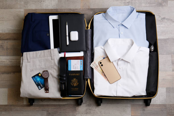istock Packed suitcase with business trip stuff on wooden surface, flat lay 1452485823