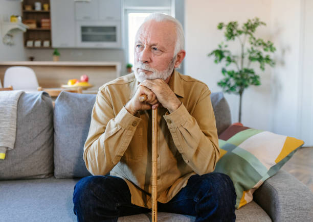istock Walking difficulties. Serious aged bearded senior man leaning on his walking stick while thinking about his helplessness, Looking away. 1452485850