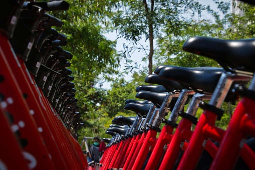 A low angle shot of a row of red bicycles with black seats parked on a rack