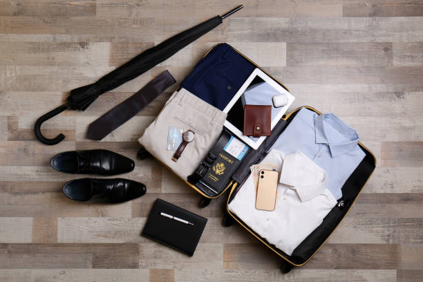 istock Packed suitcase with business trip stuff on wooden surface, flat lay 1452485941