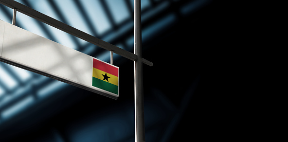 Flag of Ghana on airport departure information board. Close-up. Roof construction in the background. Blue color. Horizontal orientation. Ne people. Copy space.