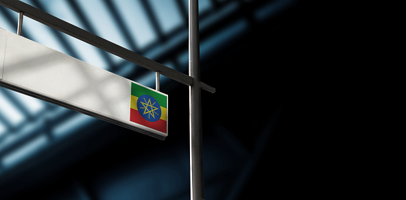 Flag of Ethiopia on airport departure information board. Close-up. Roof construction in the background. Blue color. Horizontal orientation. Ne people. Copy space.